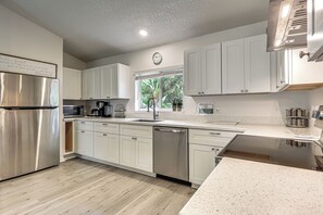 A modern kitchen with stainless steel appliances, white cabinetry, and a window with a view of greenery. - Family-friendly St. Augustine Home w/ Game Room (St. Augustine)