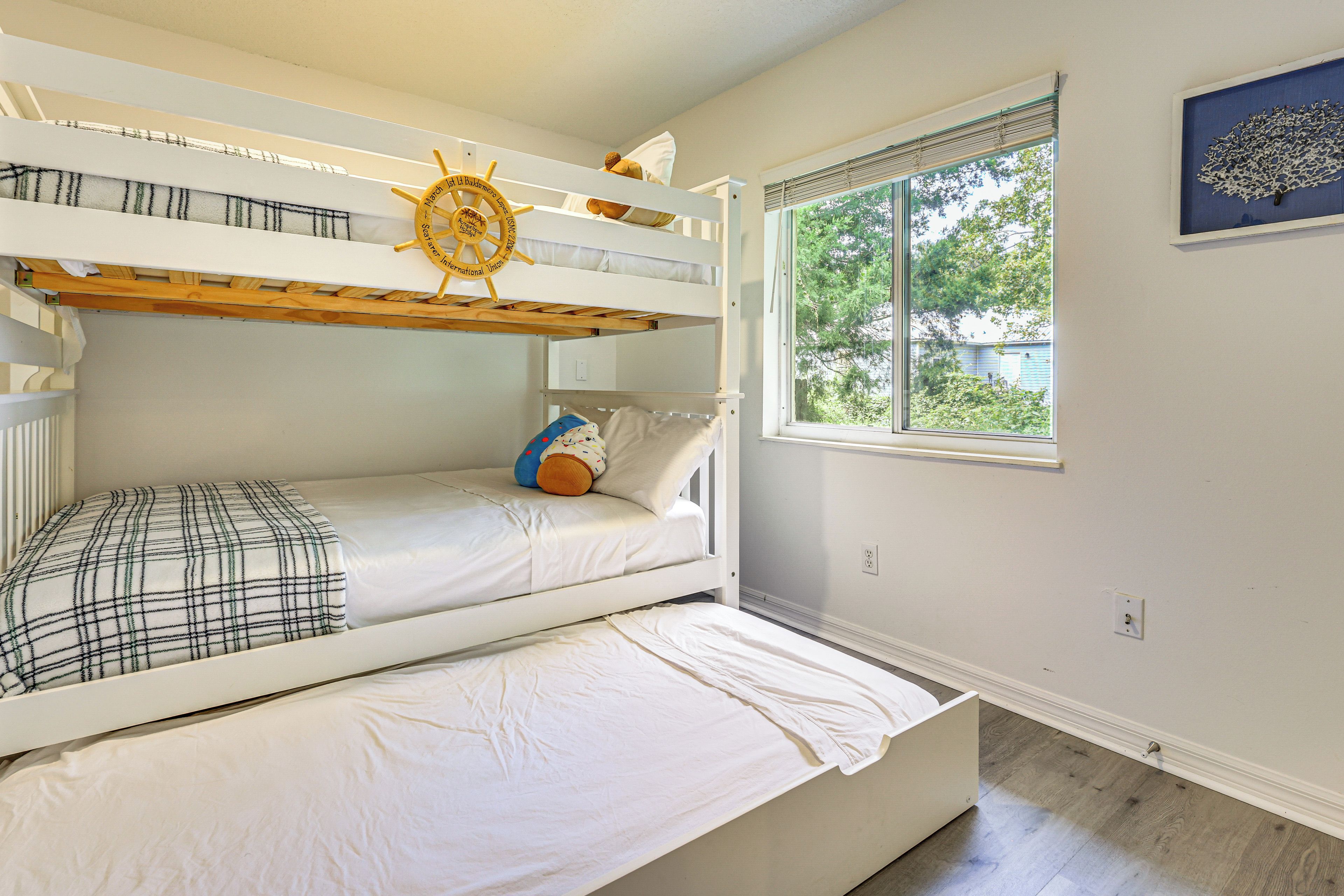Quarto com beliche e janela com vista para árvores e uma casa.