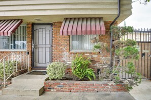 A two-story house with a brick facade, a front door, and a small front yard with plants. - Executive Oasis With In-suite Laundry Near Beach (Long Beach)