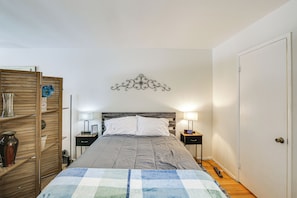 A bedroom with a bed, bedside tables, a wall decoration, and a door. - Executive Oasis With In-suite Laundry Near Beach (Long Beach)
