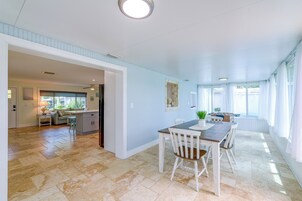 Una habitación amplia con una mesa de comedor, sillas y vistas al exterior.