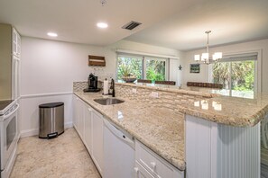A kitchen with a large island, a dishwasher, and a trash can. - Secluded Island Escape on Little Gasparilla Island (Placida)