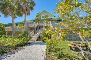 A multi-story hotel with a central staircase, outdoor seating, and a well-maintained garden. - Secluded Island Escape on Little Gasparilla Island (Placida)