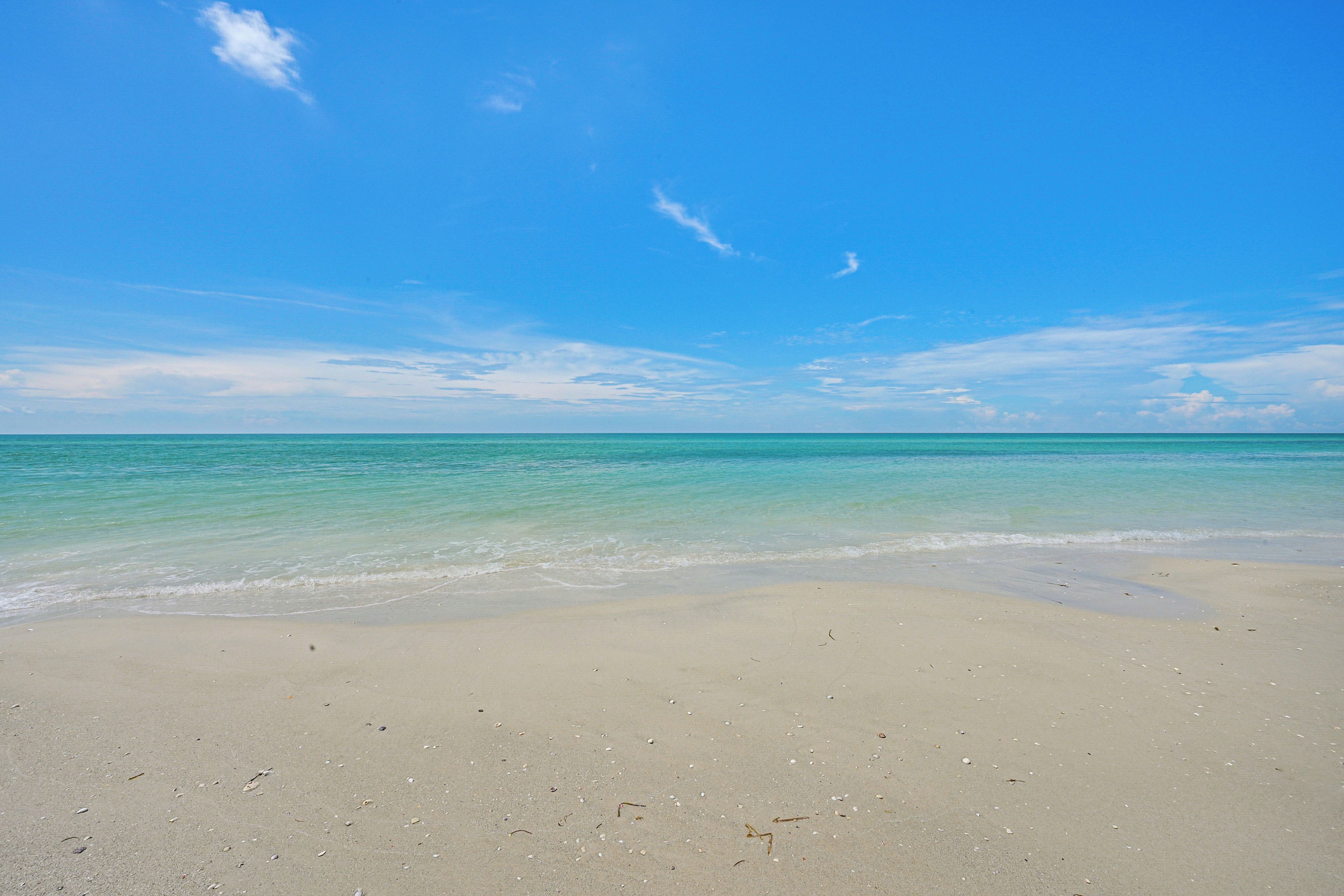 Une plage à l’eau turquoise et limpide, bordée d’un rivage sablonneux.