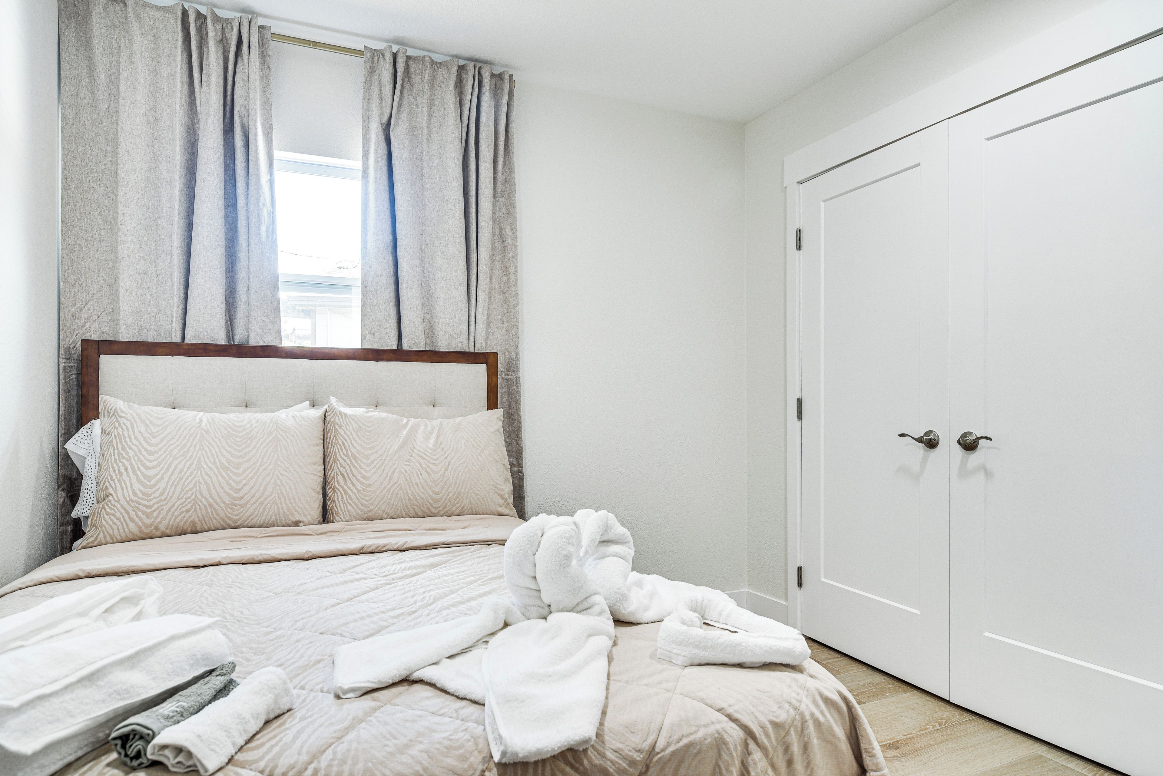 A bedroom with a bed, a wardrobe, and a window with curtains.