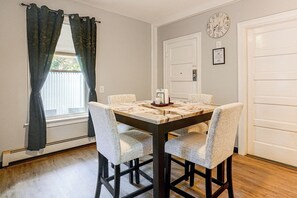 A dining area with a table, chairs, a clock, and a door. - 2-bedroom Bed & Breakfast in Adorable Lynn w/ A/C (Lynn)