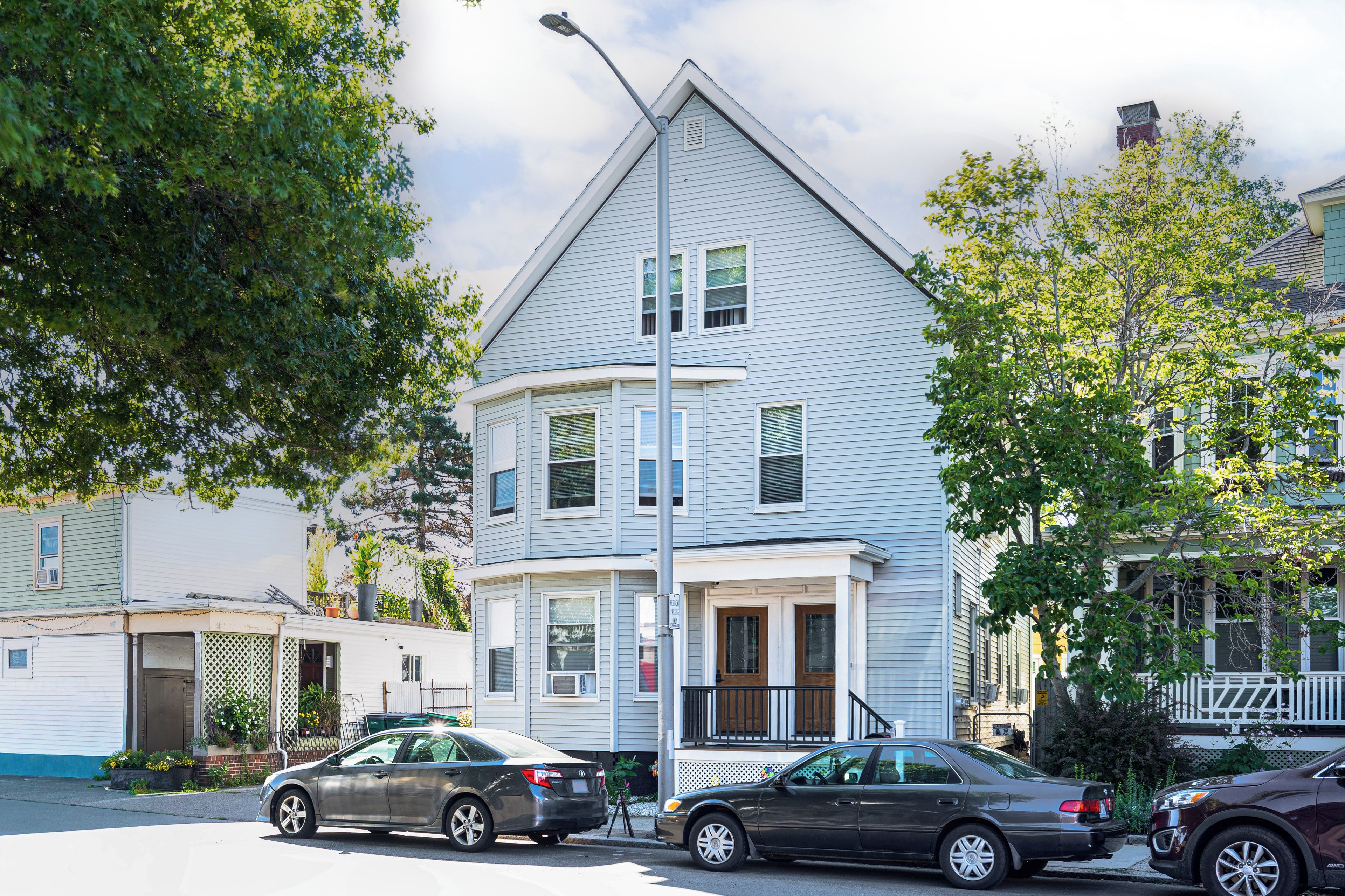 A two-story residential building with a gabled roof, a front porch, and a garage.
