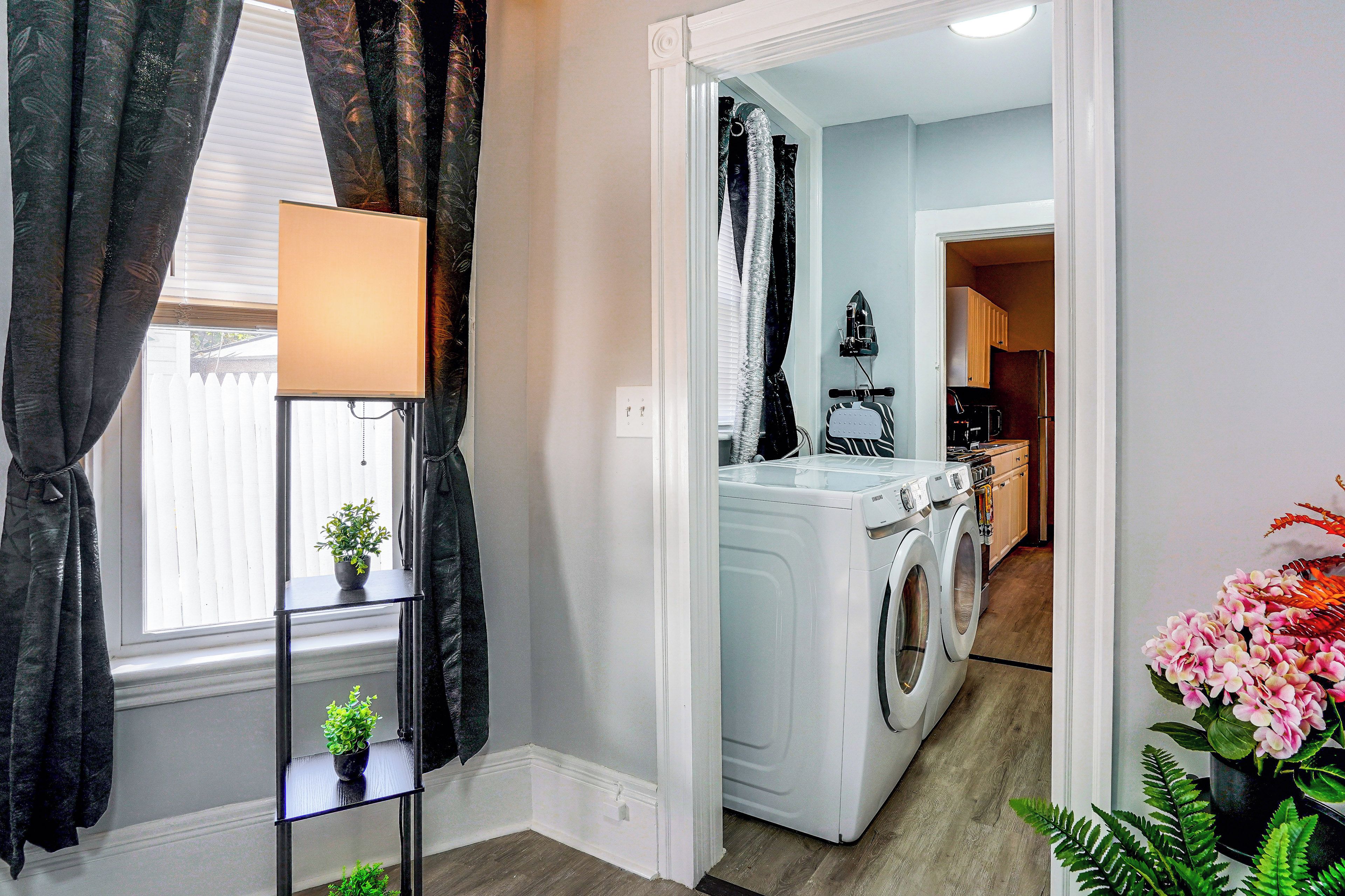 A laundry room with a washing machine and dryer, a small table with a plant, and a potted plant on the floor.