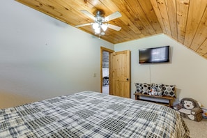 A bedroom with a bed, a ceiling fan, a television, and a door leading to another room. - 5 Mi to Cataloochee Ski! Mtn-view Retreat w/ Deck (Maggie Valley)