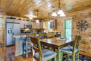 A wooden cabin interior with a kitchen, dining area, and a decorative wall piece. - 5 Mi to Cataloochee Ski! Mtn-view Retreat w/ Deck (Maggie Valley)