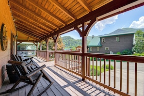 A wooden deck with benches, a covered area with a wooden ceiling, and a view of a mountain and a house. - 5 Mi to Cataloochee Ski! Mtn-view Retreat w/ Deck (Maggie Valley)