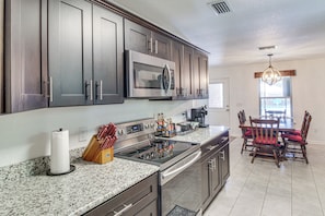 A modern kitchen with stainless steel appliances, granite countertops, and dark cabinetry. - Outdoor Oasis & Game Room! Milton Family Escape (Milton)