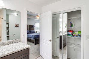 A bedroom with a bed, a dresser, and a closet containing folded clothes and toiletries. - Outdoor Oasis & Game Room! Milton Family Escape (Milton)