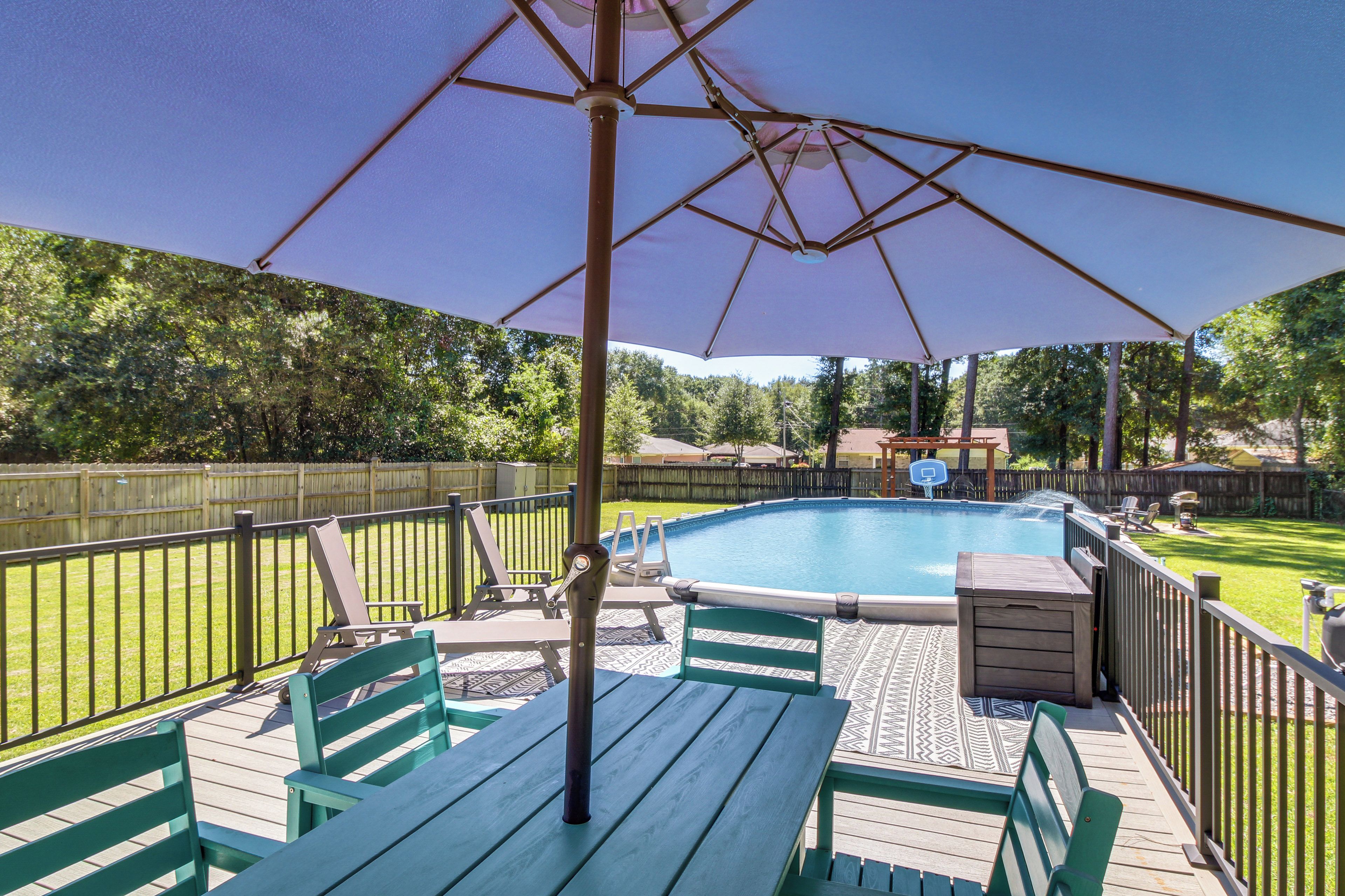 A wooden deck with a pool, surrounded by a wooden fence and trees.