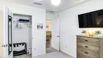 A hotel room with a closet, a wooden dresser, a flat-screen TV, and a ceiling fan.
