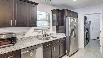 A modern kitchen with dark cabinetry, stainless steel appliances, and a granite countertop.