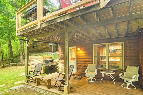 A wooden cabin with a porch, outdoor grill, and seating area.
