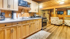 Un interior de madera con una zona de cocina equipada con estufa, microondas y varios electrodomésticos.