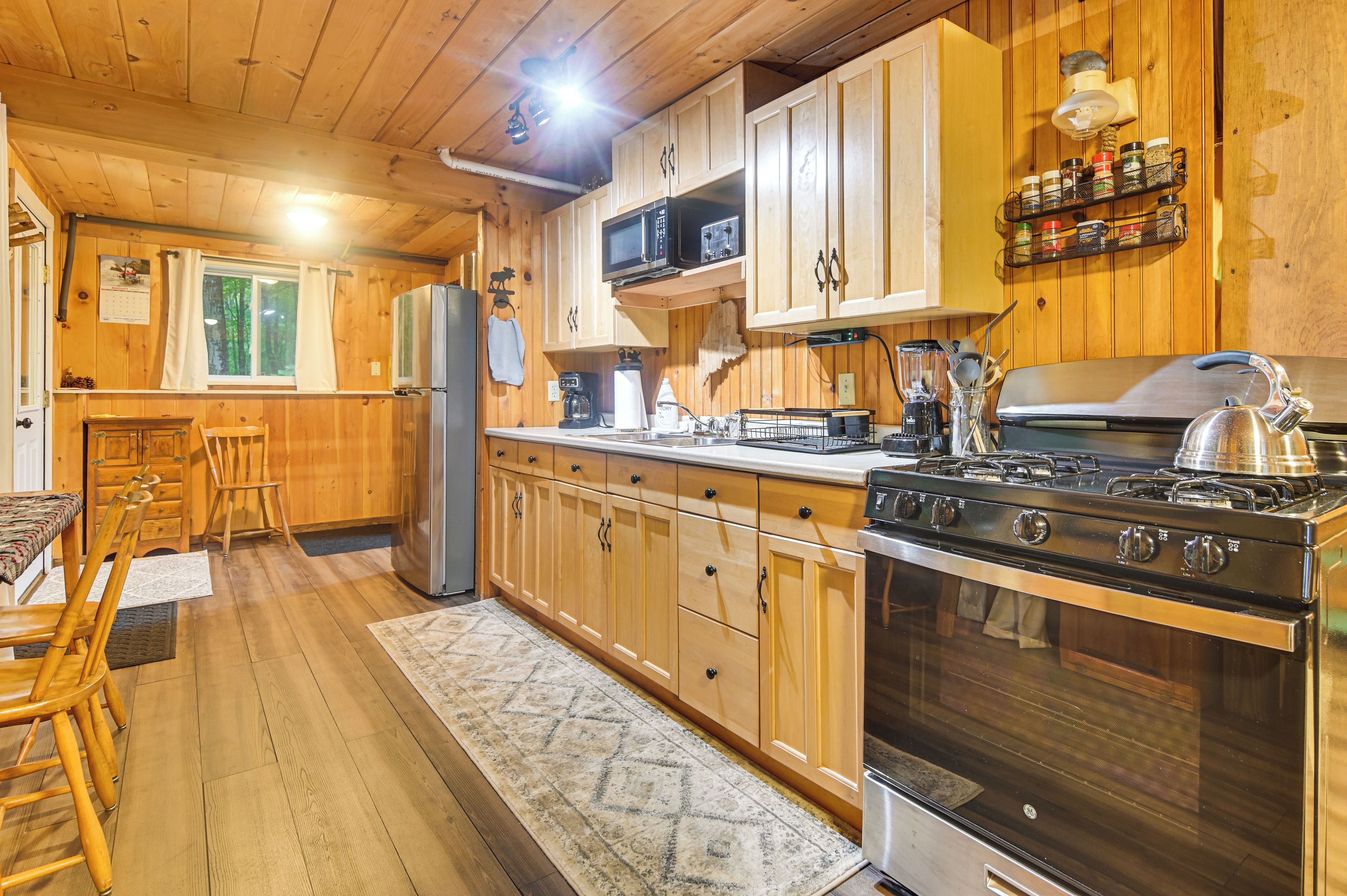 Un intérieur en bois avec une cuisine équipée d’une cuisinière, d’un réfrigérateur et de meubles de rangement en bois.