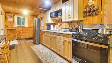 A wooden interior with a kitchen featuring a stove, refrigerator, and wooden cabinets.