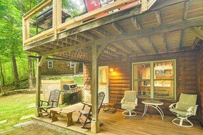 Una cabaña de madera con terraza, parrilla exterior y zona de estar.