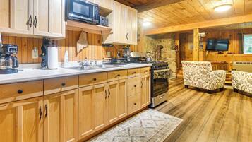 A kitchen with wooden cabinets, a microwave, a stove, and a sink. There is a patterned rug on the floor.