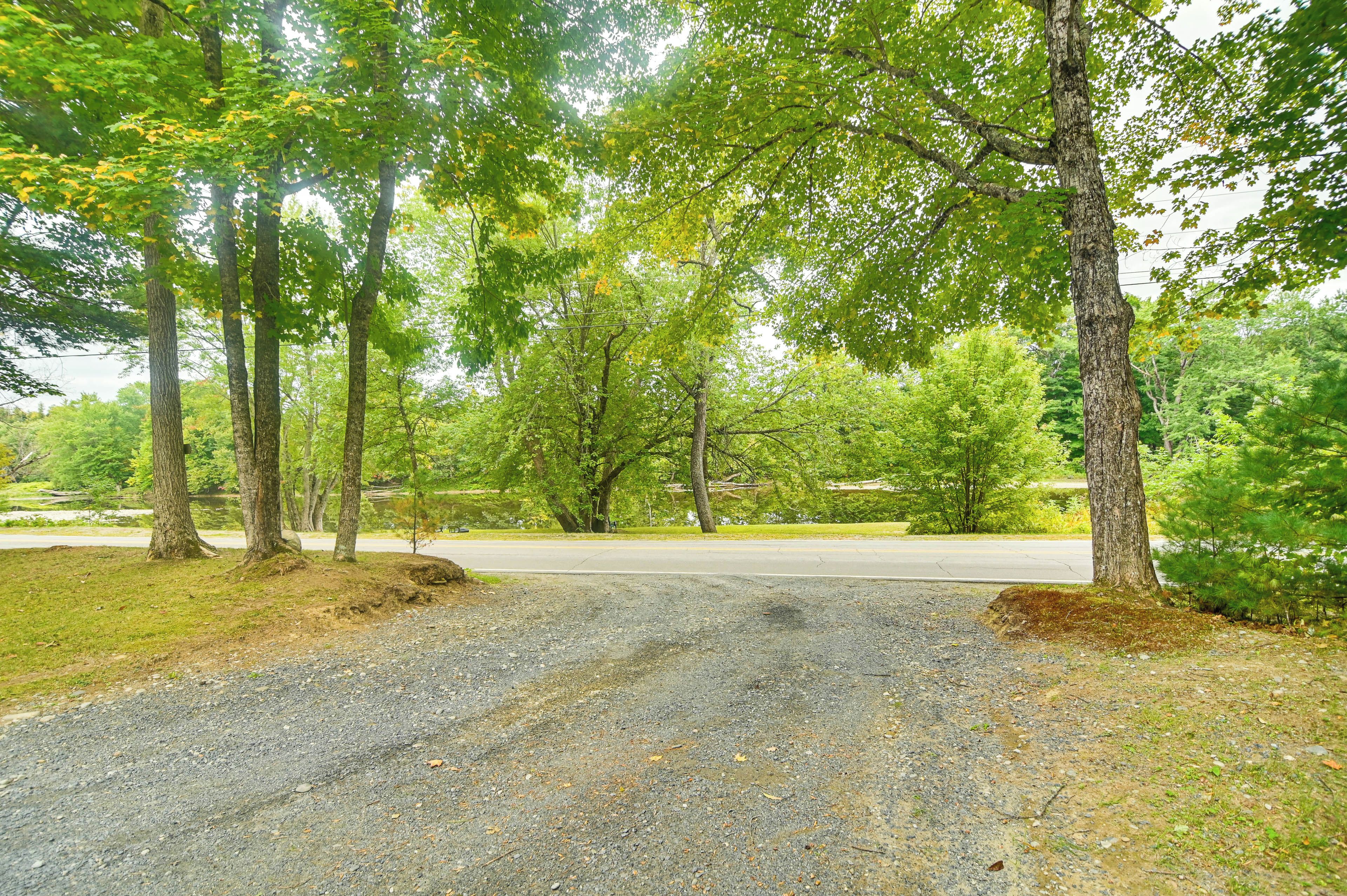 A gravel road leading to a parking area surrounded by trees.