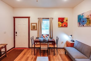 A dining area with a table set for two, a sofa, and a painting on the wall. - Cozy Apartment Near UAF & Downtown Fairbanks! (Fairbanks)