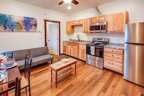 A compact kitchen with wooden cabinets, a stainless steel refrigerator, and a built-in oven. - Cozy Apartment Near UAF & Downtown Fairbanks! (Fairbanks)