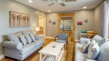 A modern living room with a grey sofa, a coffee table, and a ceiling fan.