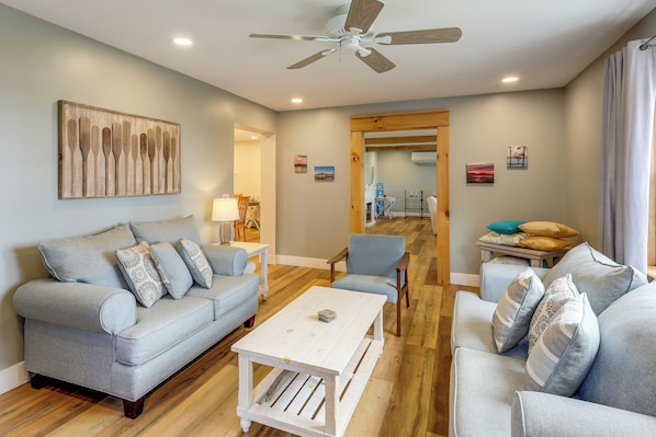A modern living room with a grey sofa, a coffee table, and a ceiling fan.