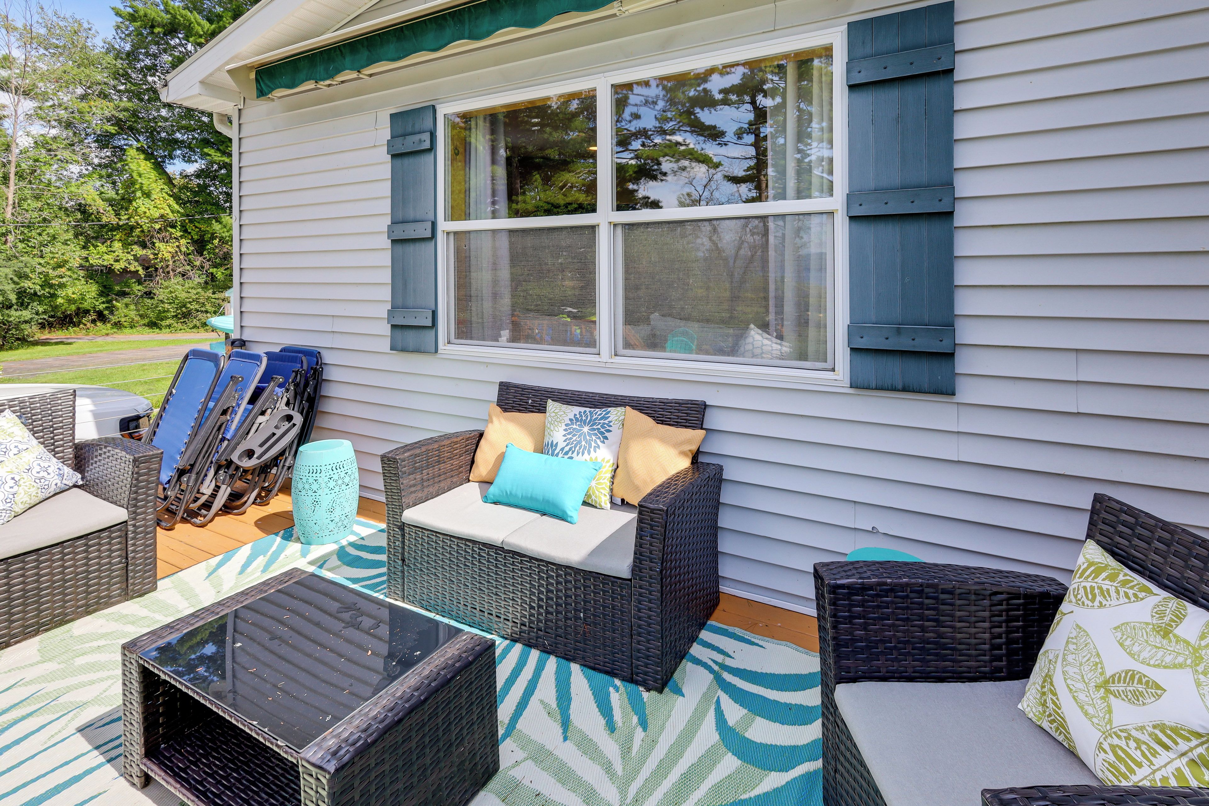 A covered patio area with wicker furniture and a glass table.