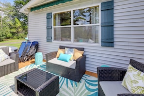 A covered patio area with wicker furniture and a glass table. - Lakefront Adirondack Escape! Fire Pit & Game Room (Broadalbin)