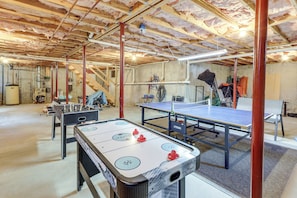 A spacious room with a pool table, foosball table, and a ping pong table.