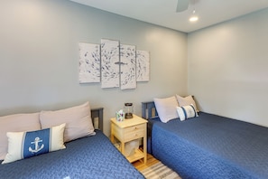 A bedroom with two beds, a nightstand, and wall art.