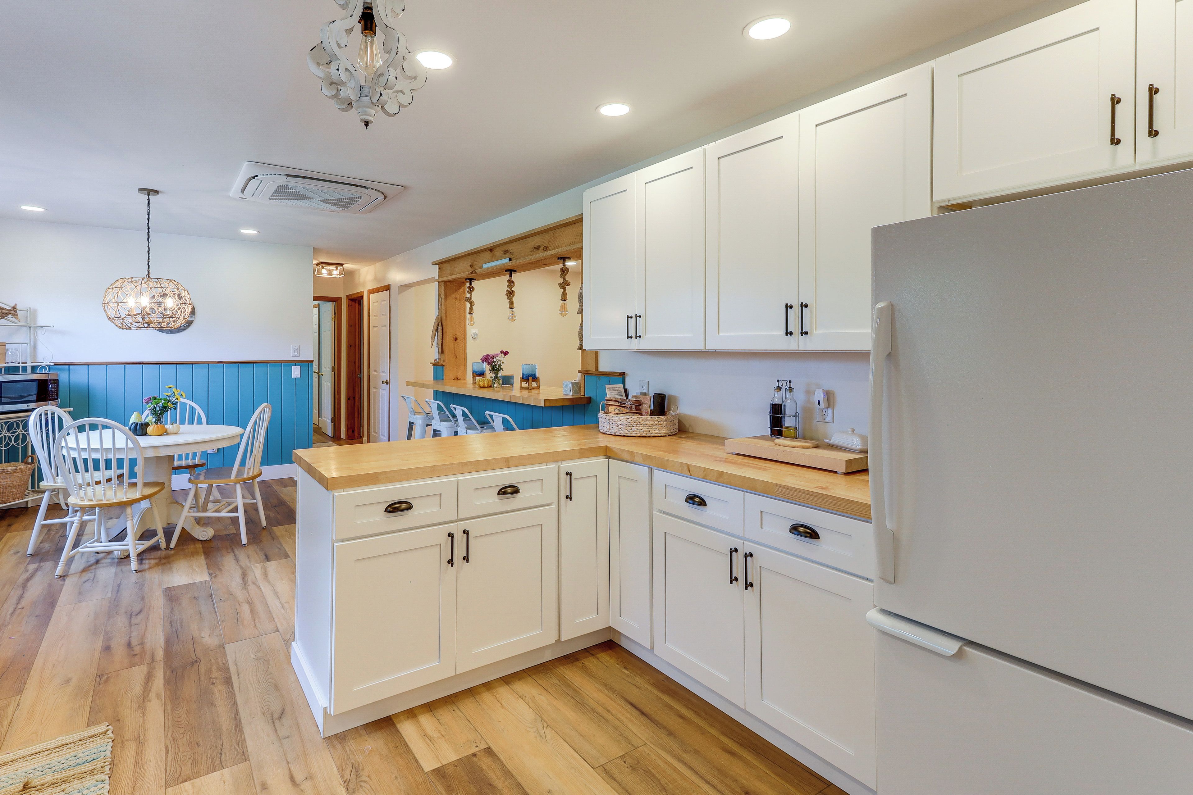 A modern kitchen with white cabinetry, a wooden countertop, and a built-in refrigerator.
