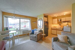 A compact living space with a dining area, a sofa, a kitchen, and a view of a building with a sign that reads 'Welcome to the Lake.' - Lakefront Studio, 3 Mi to Petoskey State Park! (Conway)