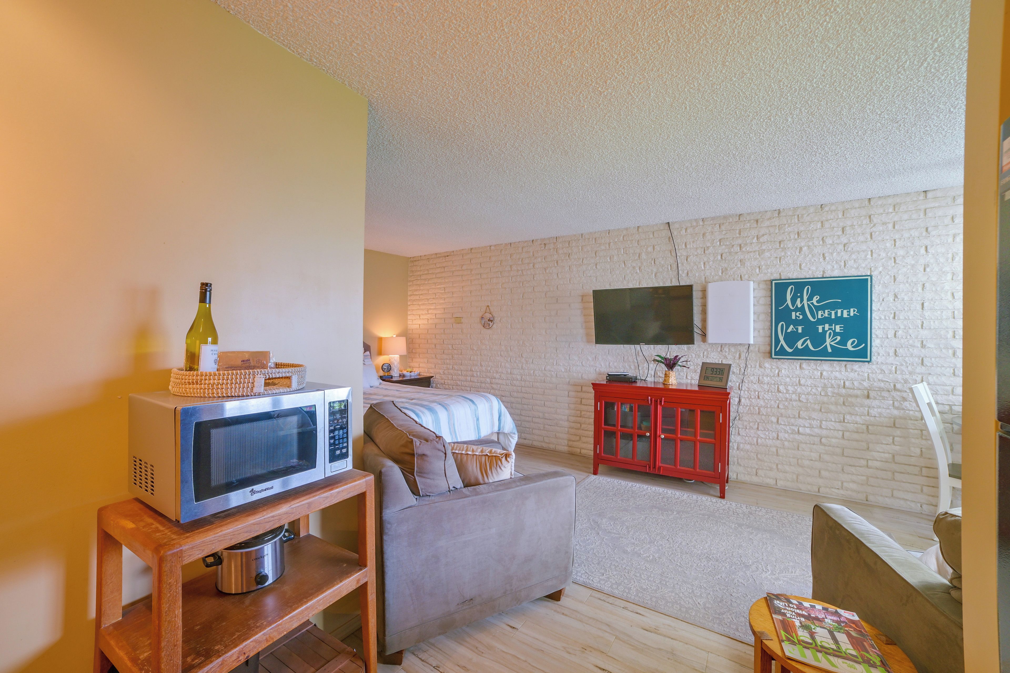 A cozy living room with a sofa, a red cabinet, a television, and a microwave on a wooden stand.