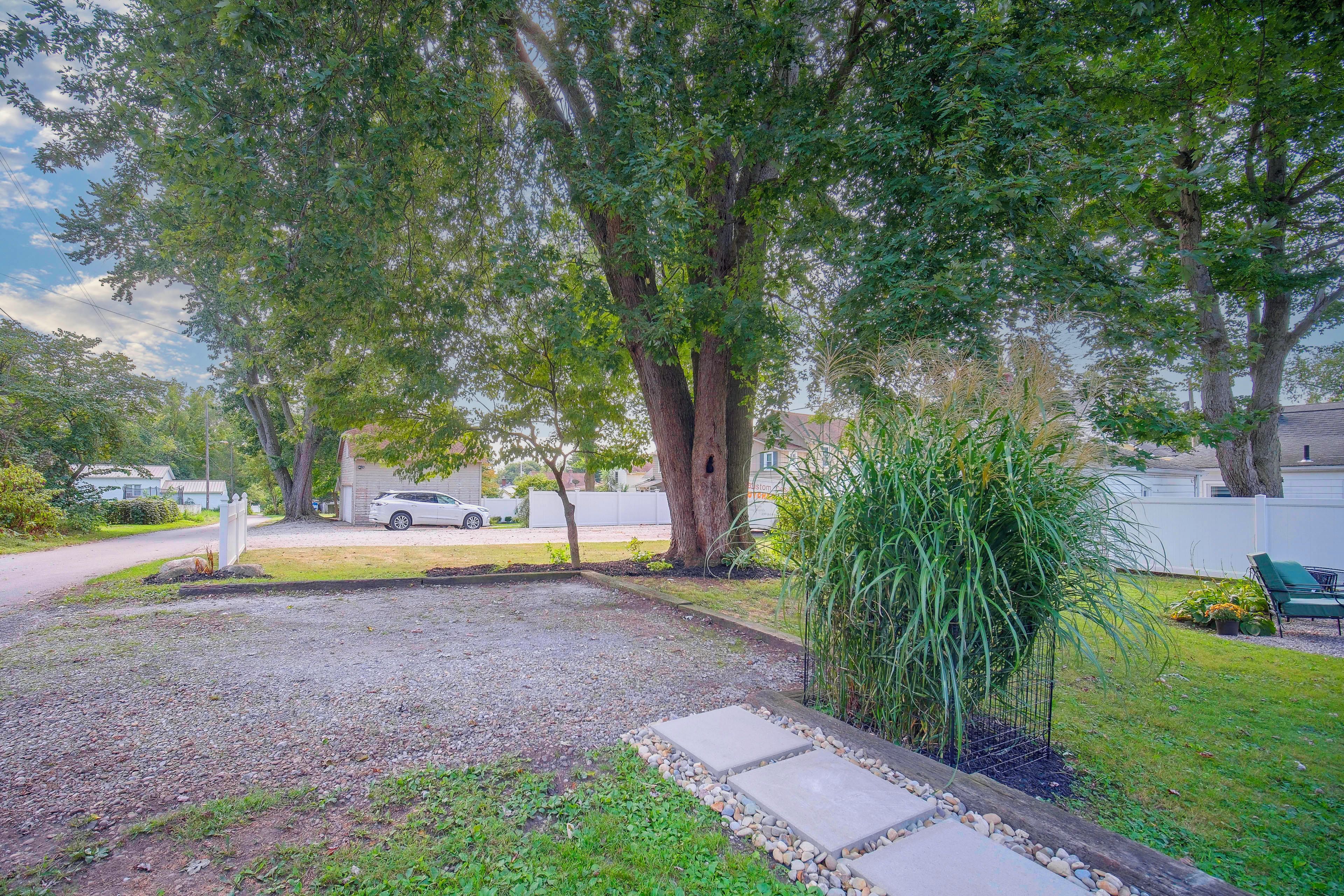 A residential outdoor area with a gravel path, a lawn, and a large tree.