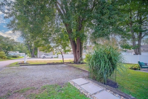 A residential outdoor area with a gravel path, a lawn, and a large tree. - Hot Tub Haven in Wooster: Walk to Shops & Eats! (Wooster)