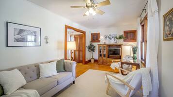 A living room with a sofa, a wooden cabinet, a television, and a ceiling fan.