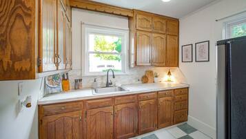 A kitchen with wooden cabinets, a sink, a window, and a refrigerator.