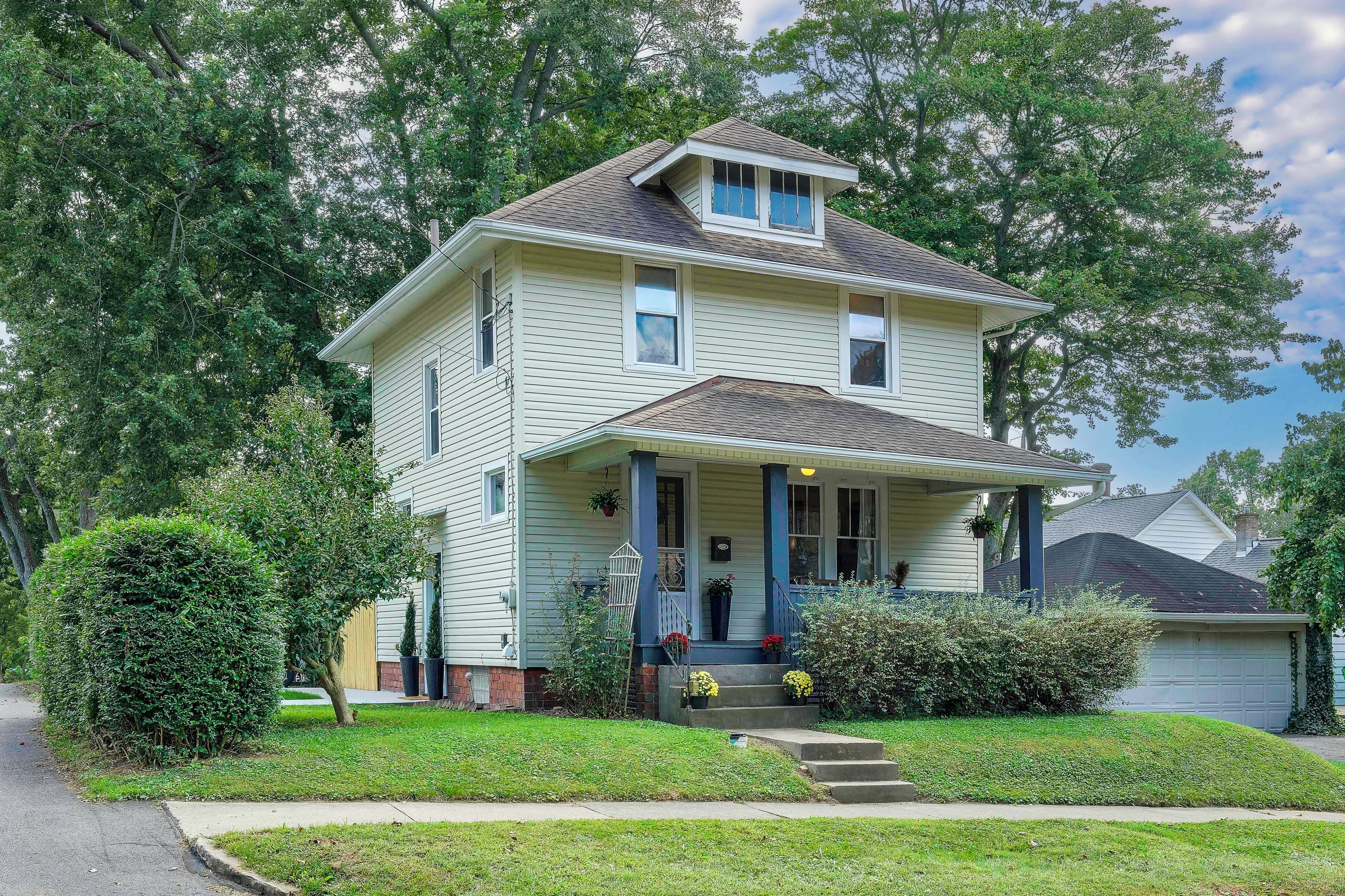 A two-story house with a front porch, a garage, and a well-maintained lawn.