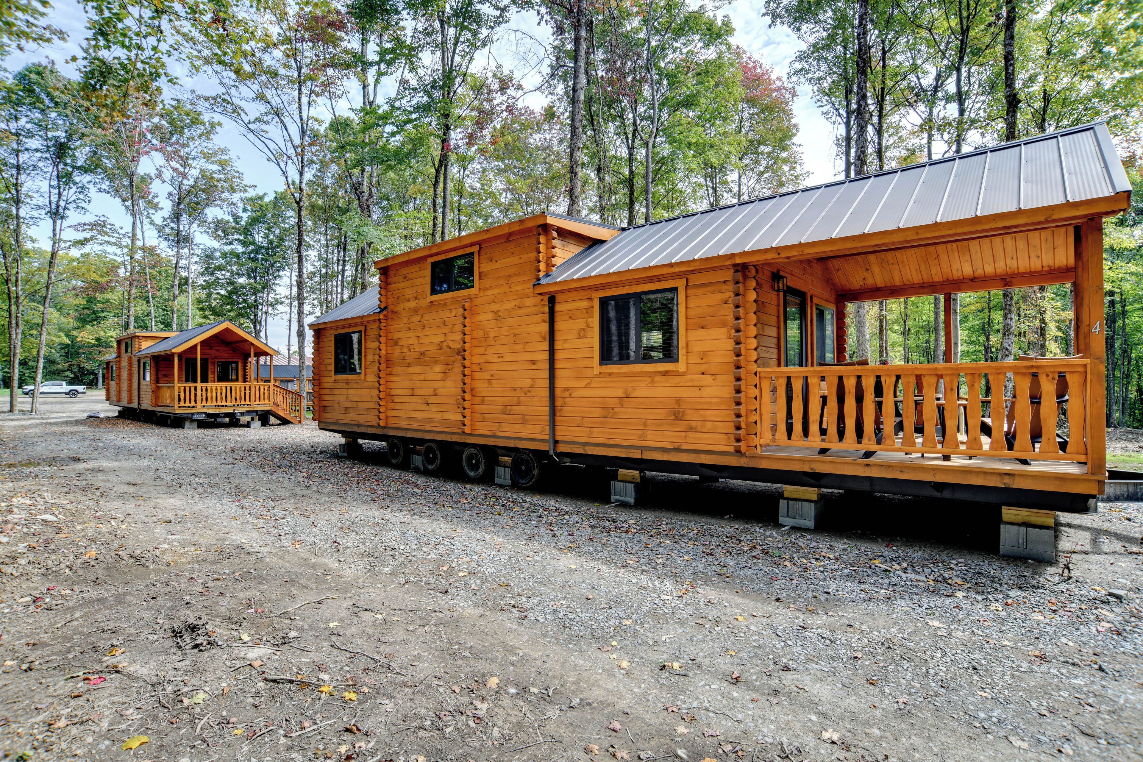 A wooden cabin with a balcony, set in a forested area.