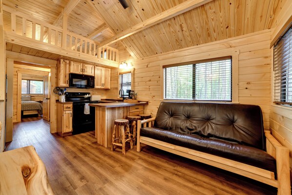 A cabin interior with a kitchen, dining area, and a sofa. - Hike, Bike & Stargaze! Oxford Cabin w/ Fire Pit (Oxford)