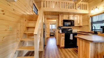 A wooden interior with a kitchen, a dining area, and a staircase.