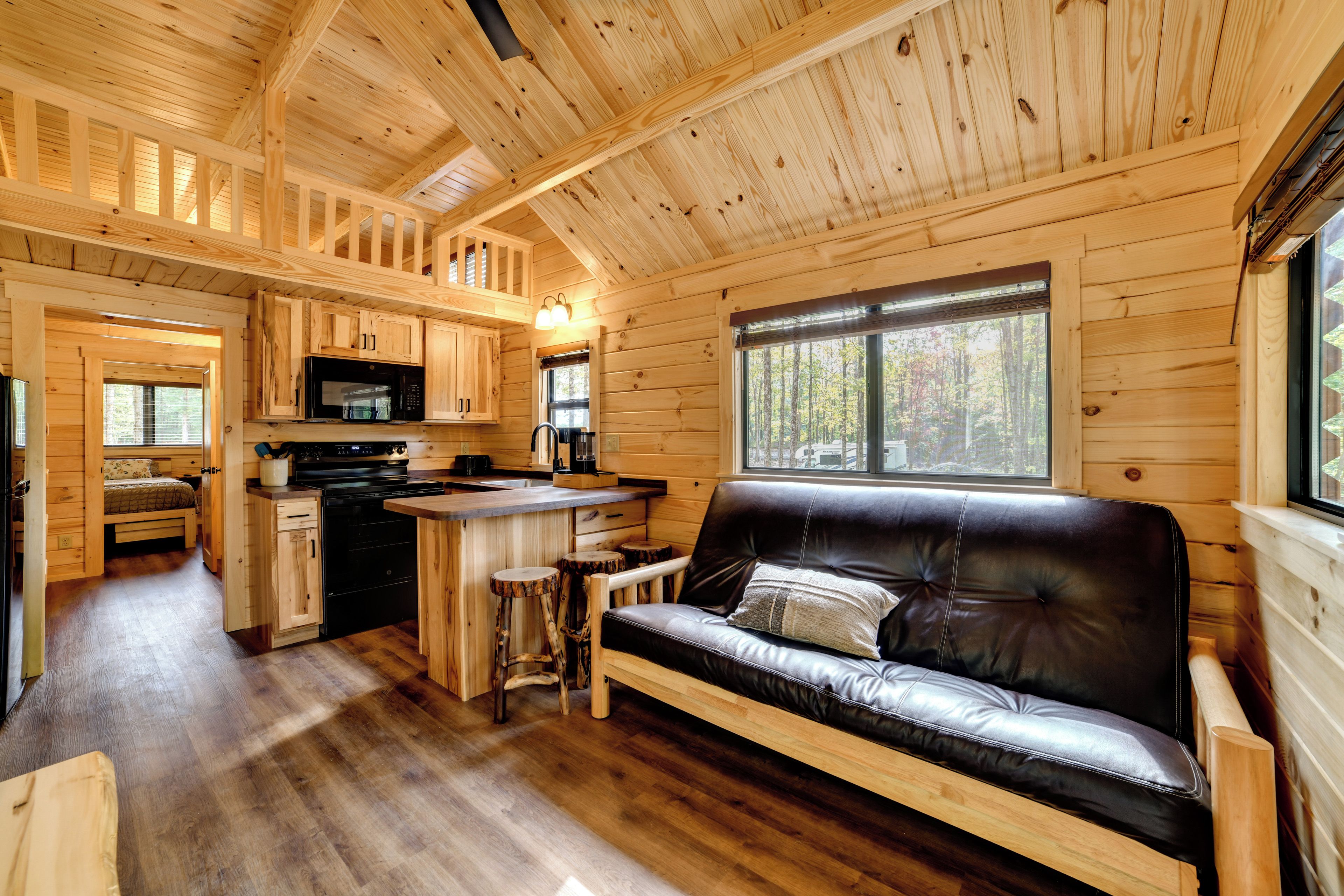 A cabin interior with a kitchenette, a dining area, and a seating area with a sofa and stools.