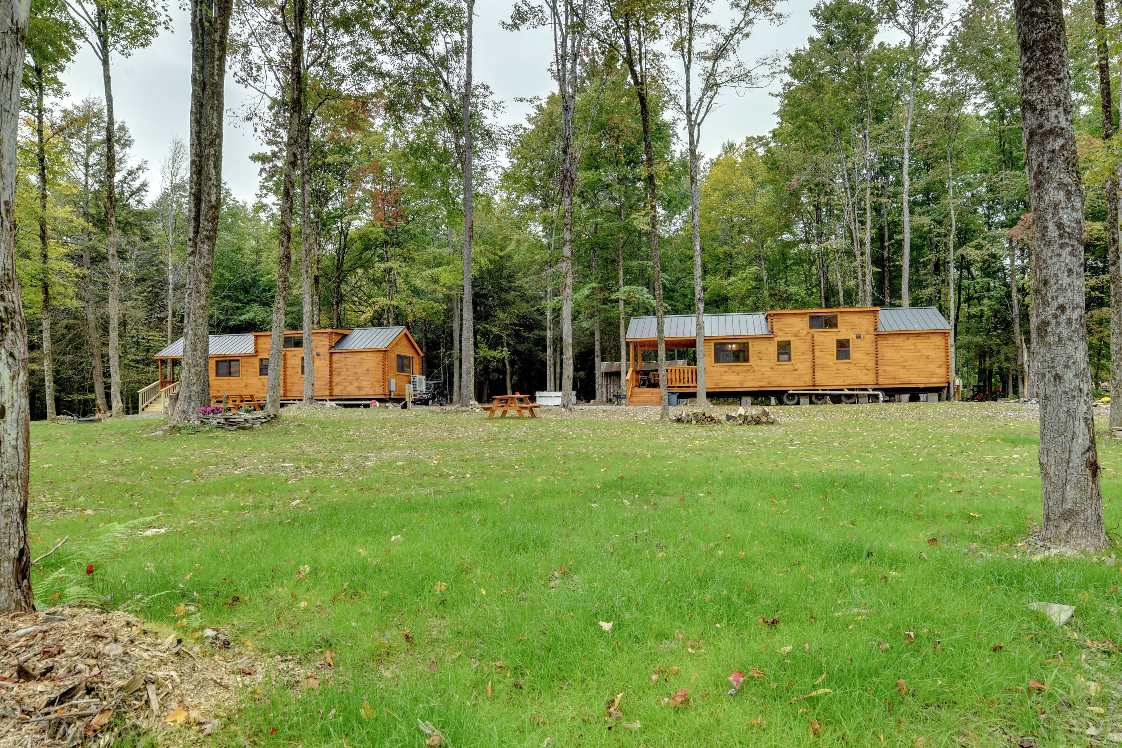 A cabin with a deck, surrounded by a forest.