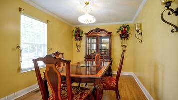 A dining room with a wooden table and chairs, a chandelier, and wall-mounted sconces.