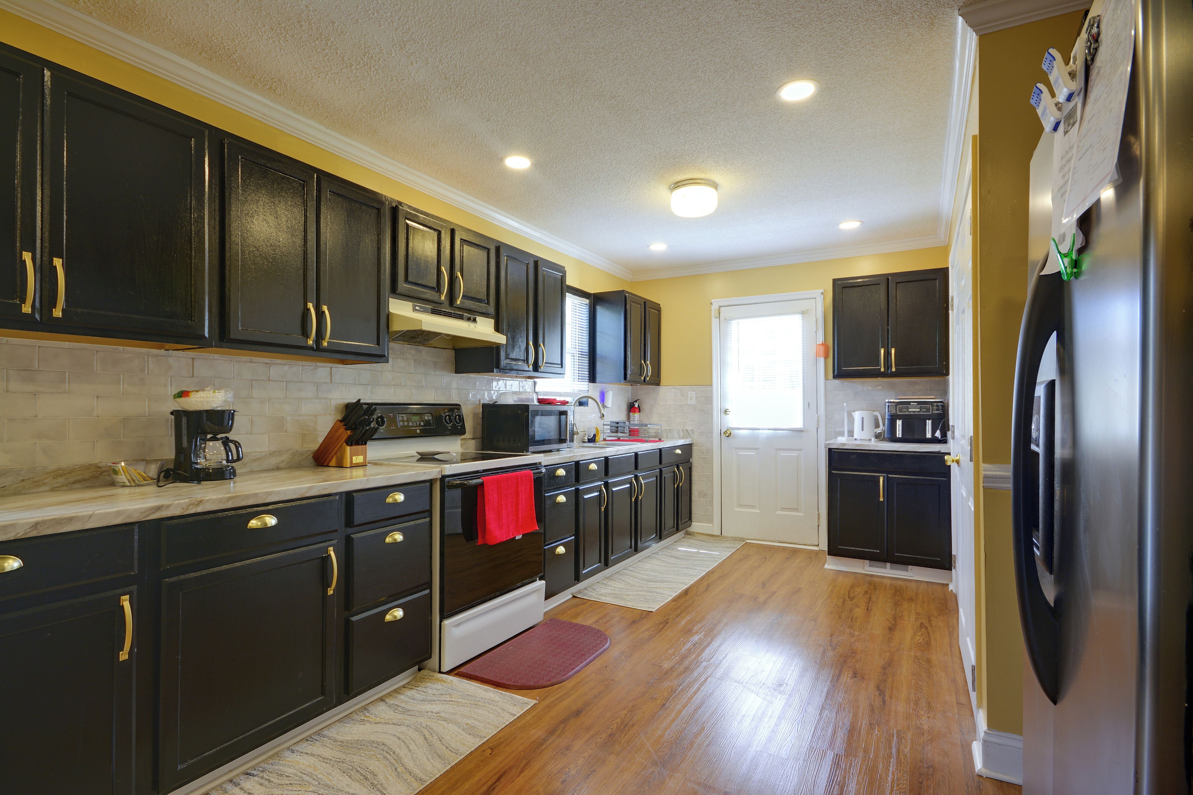 A kitchen with dark cabinetry, a refrigerator, a microwave, and a stove.